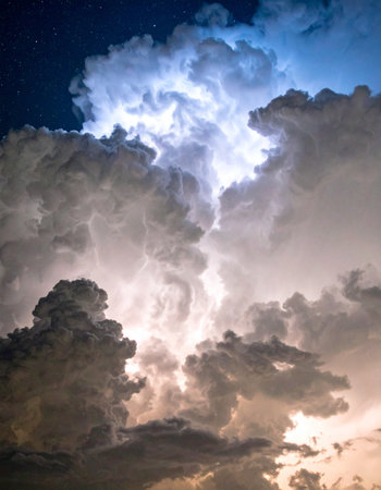 Deep within a turbulent cloud mass, a silent explosion of light illuminates its complex structures. This celestial event showcases natures immense power and dramatic, awe-inspiring beauty against the darkness.の素材