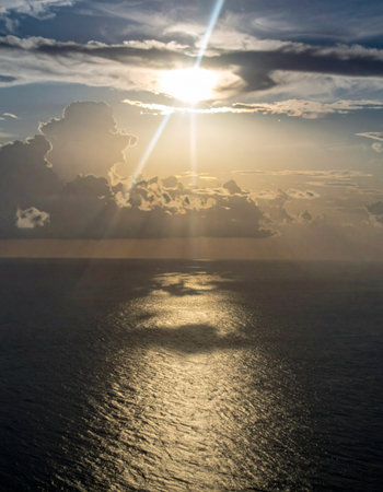 Golden sunbeams pierce through a dramatic cloudscape, casting a brilliant path of light across the tranquil ocean surface. This awe-inspiring scene evokes feelings of hope, spirituality, and the profound beauty of a new day dawning or a peaceful days end.の素材