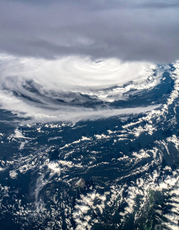 From the quiet vantage point of space, a powerful hurricane churns the ocean below. The immense, swirling vortex of clouds showcases the raw, untamed power of nature, a dramatic and awe-inspiring spectacle of weather in motion.の素材