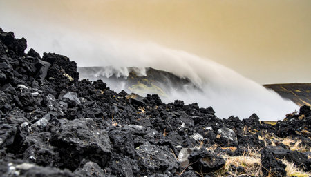 A powerful plume of geothermal steam erupts from a volcanic vent, billowing across a stark and primal landscape of sharp, black lava rock. This dramatic scene captures the raw, untamed energy of the Earth, showcasing a moment of geological creation and immense natural force.の素材