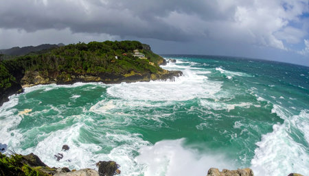 From a high vantage point, witness the raw power of nature as a turbulent turquoise sea, whipped into a frenzy by a passing storm, relentlessly crashes against a rugged, forested coastline. The dramatic, cloud-filled sky adds to the epic and untamed beauty of this wild coastal landscape.の素材