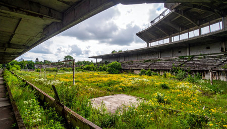 Once filled with the roar of the crowd, this forgotten stadium now stands in silence. Nature has reclaimed the field and stands, with wildflowers and weeds growing where athletes once competed, creating a powerful and melancholic scene of decay and rebirth.の素材