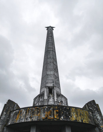 A low-angle view of the historic Tugu Pahlawan, or Heroes Monument, in Surabaya, Indonesia. The weathered obelisk stands tall against a dramatic, overcast sky, symbolizing the nations struggle for independence and serving as a solemn reminder of sacrifice and heroism.の素材