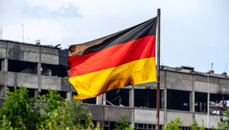 The vibrant German flag waves defiantly in the wind, a powerful symbol of national pride and resilience set against the somber backdrop of a derelict and damaged building. This poignant scene captures a story of survival, hope, and the enduring spirit of a nation through times of crisis and reconstruction.の素材