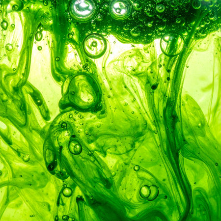 A vibrant green substance swirls and dissolves in a clear liquid, creating an otherworldly dance of color and light. Trapped air bubbles rise through the dynamic fluid, suggesting life, energy, or a scientific reaction in progress. This abstract macro view captures a moment of beautiful chaos.の素材