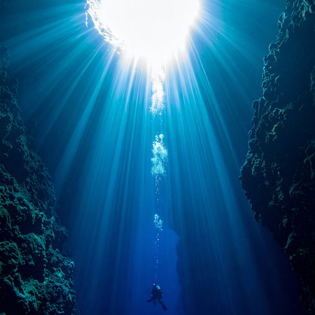A lone scuba diver ascends from the mysterious depths of a deep blue hole, guided by breathtaking sunbeams that pierce the tranquil water. This image captures a moment of awe, adventure, and the profound beauty of exploring the hidden underwater world.の素材