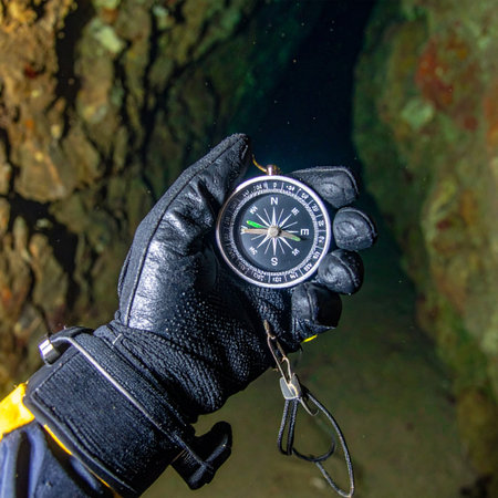 A first-person view of an adventurer holding a compass, seeking direction in the deep, mysterious darkness of an underground cave. This image captures the essence of exploration, survival, and the challenge of finding ones path in an unknown environment.の素材