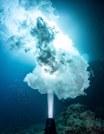 A dramatic underwater scene captures the immense power of a hydrothermal vent as it erupts with a massive plume of superheated water and minerals from the dark ocean floor, illuminating the deep sea with its raw energy.の素材