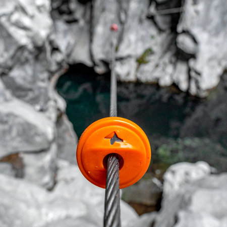 The moment of truth arrives. A bright orange pulley is the only thing between you and a thrilling flight over the deep, rocky canyon below. A first-person perspective captures the heart-pounding anticipation before taking the leap into an unforgettable adventure.の素材