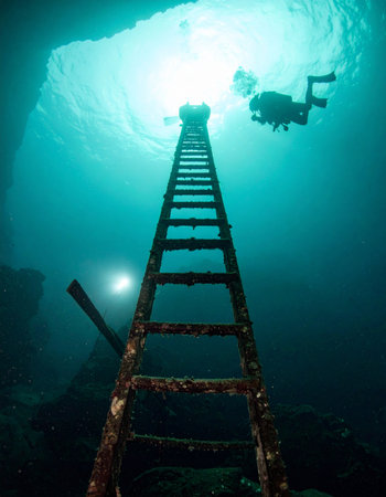 From the mysterious depths, a lone scuba diver ascends a submerged ladder, a surreal pathway leading towards the bright, hopeful light of the surface. This conceptual image represents a journey of discovery, overcoming challenges, and finding an unexpected way to freedom and success.の素材