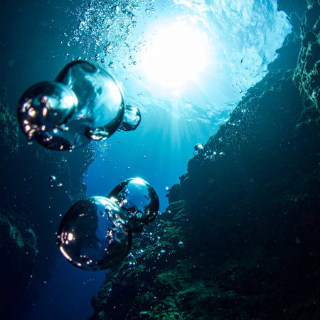 From the dark, silent depths, shimmering spheres of air begin their journey upwards. They float gracefully through the deep blue, drawn towards the brilliant sunburst at the surface, symbolizing a hopeful ascent towards freedom, clarity, and a new beginning.の素材