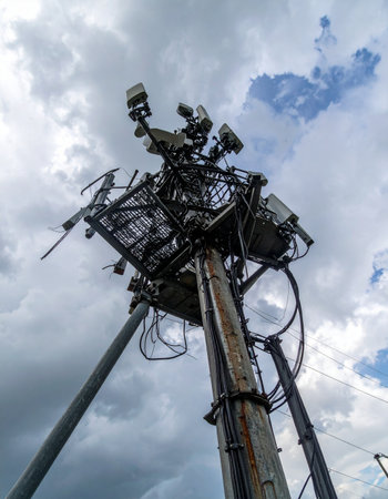 A silent sentinel of the digital age, this complex tower stands guard against a dramatic sky. Its array of cameras and antennas constantly monitors and transmits data, representing the backbone of modern communication, security, and the ever-watchful eye of technology.の素材