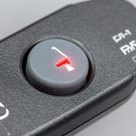 A macro shot captures the moment of activation as a small red LED indicator lights up on a remote control button.の素材