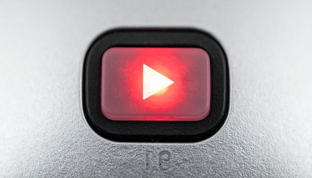 A close-up of an illuminated red play button, the universal symbol for digital video content.の素材