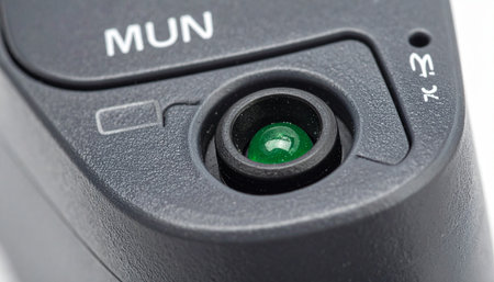 A detailed macro shot captures a glowing green indicator light on a modern electronic device.の素材