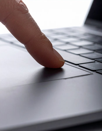 A close-up shot captures the decisive moment a finger presses a key on a sleek, modern laptop.の素材