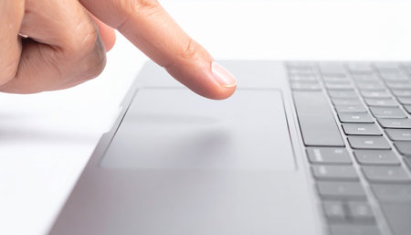 A close-up shot captures the precise moment a user's finger makes contact with a sleek laptop trackpad.の素材