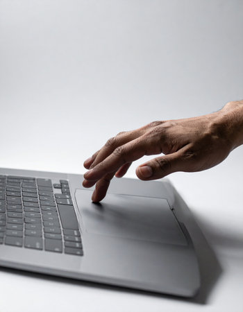 A close-up shot captures a person's hand interacting with the sleek touchpad of a modern laptop.の素材