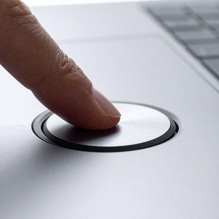 A close-up view captures a user's finger pressing a biometric scanner on a sleek, modern laptop.の素材