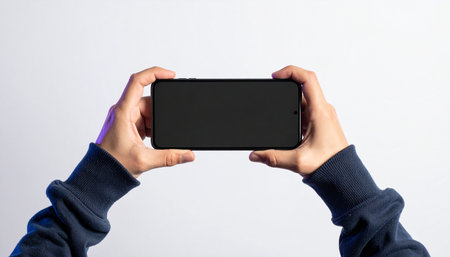 A first-person perspective of someone holding a modern smartphone horizontally, ready to watch a video, play a game, or stream content.の素材