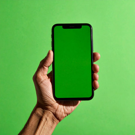 A person's hand holds a modern smartphone, presenting its vibrant green screen forward.の素材