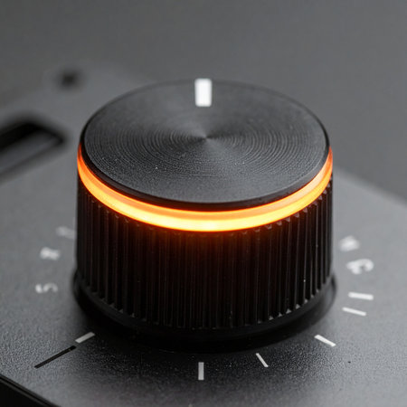 A close-up of a precision control dial, its textured black surface catching the light. A warm orange LED ring glows, indicating an active setting on a high-end piece of electronic equipment.の素材