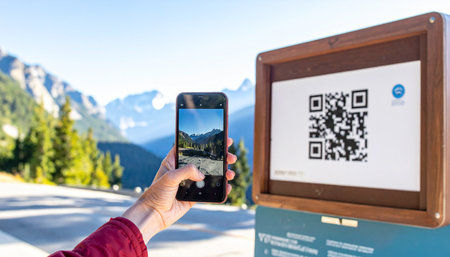 A traveler uses their smartphone to scan a QR code at a scenic mountain overlook.の素材