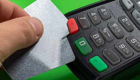 A close-up shot captures the moment of a secure transaction as a customer inserts their credit card into a modern point-of-sale terminal.の素材