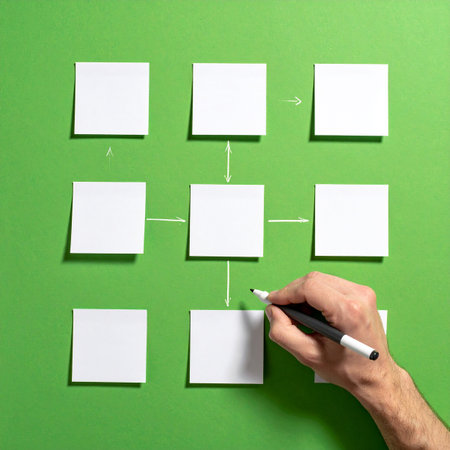 From a top-down perspective, a hand meticulously draws connecting lines between blank white sticky notes, creating a flowchart or mind map.の素材