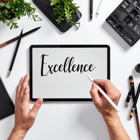 From a top-down perspective, a creative professional uses a stylus to write the word 'Excellence' on a digital tablet.の素材