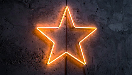 An orange neon star glows brightly against a dark, textured concrete wall, casting a warm and inviting light.の素材