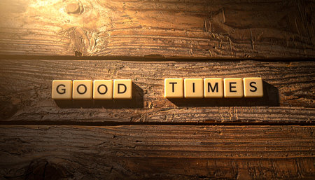 Wooden letter blocks spell out the phrase 'Good Times' on a rustic wood background.の素材