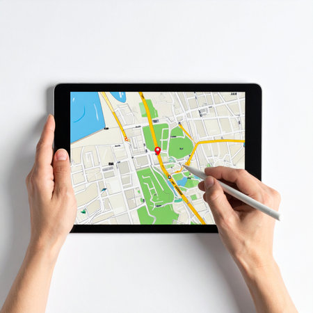 From a top-down perspective, a person uses a stylus to pinpoint a destination on a digital city map displayed on a tablet.の素材