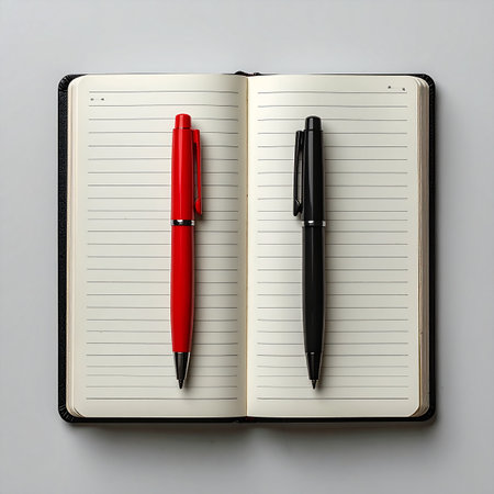 A moment of decision captured from above. A red pen and a black pen lie on opposite pages of a blank, lined journal, symbolizing a choice between two ideas, paths, or perspectives.の素材