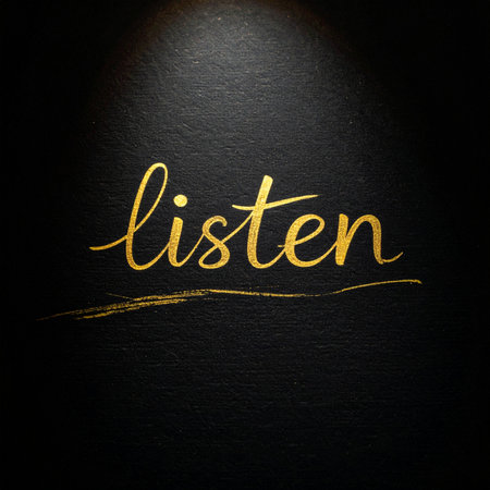 The word 'listen' is elegantly written in shimmering gold calligraphy, illuminated by a soft spotlight against a dark, textured slate background.の素材