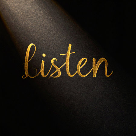 In a quiet, dark space, a single beam of light illuminates the word 'listen' in elegant golden script.の素材
