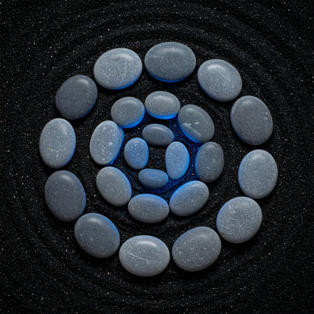 Smooth, glowing stones form a perfect spiral on a bed of raked black sand, creating a tranquil and meditative scene.の素材