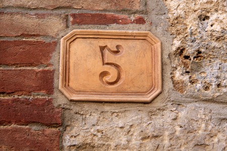 Street number five out of clay on a house in Tuscany in San Gimignanoの写真素材