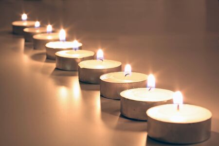 White tea lights in a row in front of a silver background as a Christmas decorationの写真素材