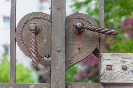 Old rusty door handle in heart shape on a large iron portalの写真素材
