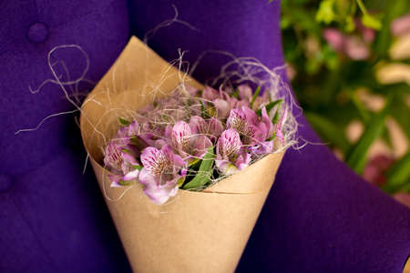 Bouquet of alstroemeria wrapped in craft paper lying on a chairの写真素材