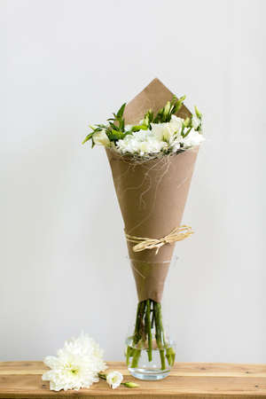 Paper cornet with a bouquet of white lisianthus in a glass vaseの写真素材