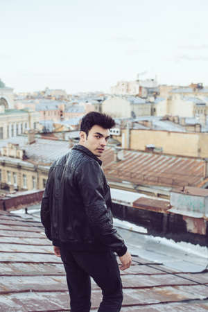 Man in a leather jacket on a rooftop in the center of the cityの写真素材