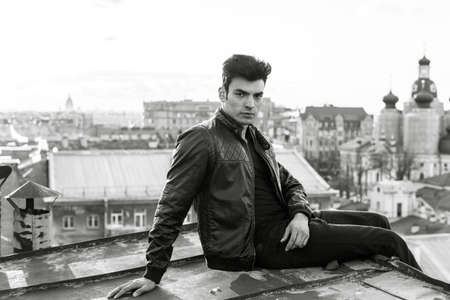 Man in a leather jacket on a rooftop in the center of the cityの写真素材