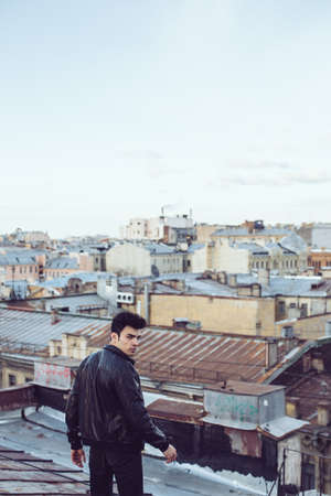 Man in a leather jacket on a rooftop in the center of the cityの写真素材