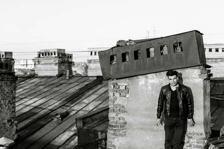 Man in a leather jacket on a rooftop in the center of the cityの写真素材
