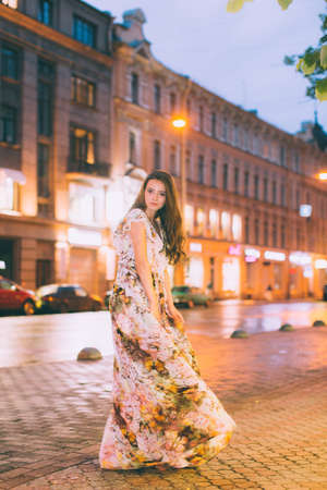 Beautiful woman in gorgeous dress against the backdrop of the city at night. Motion effect.の写真素材
