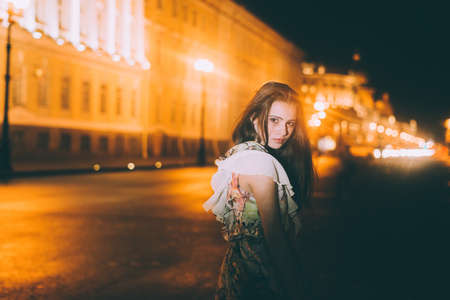 Beautiful woman in gorgeous dress against the backdrop of the city at night. Motion effect.