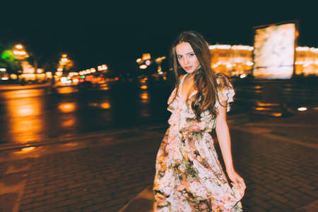 Beautiful woman in gorgeous dress against the backdrop of the city at night. Motion effect.