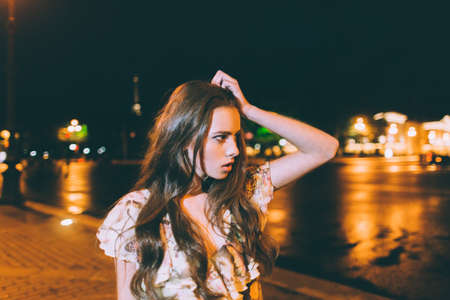 Beautiful woman in gorgeous dress against the backdrop of the city at night. Motion effect.の写真素材
